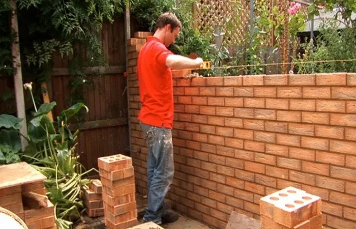 Công nhân đang tiến hành xây tường gạch với mạch vữa đều đặn