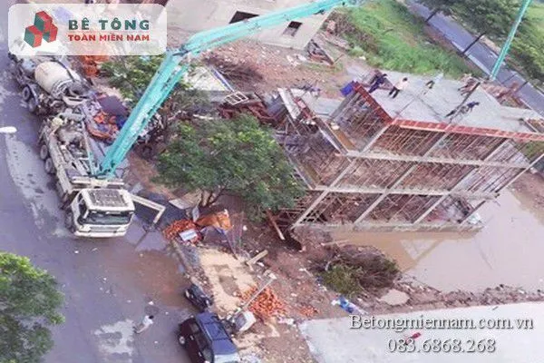 Nhân viên kỹ thuật đang điều khiển vòi bơm công suất lớn để phân bổ bê tông đều khắp mặt sàn tại Thủ Đức