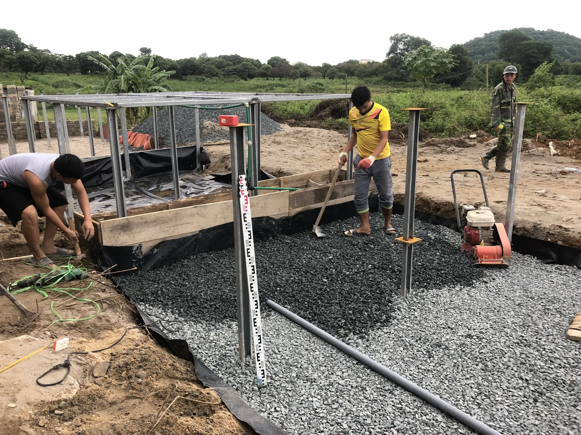 Công nhân tiến hành lắp đặt hệ thống ống thoát nước đục lỗ dưới đáy móng